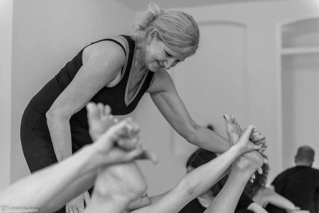 Lehrerin korrigiert mit den Händen die Haltung einer Schülerin im athayoga Studio