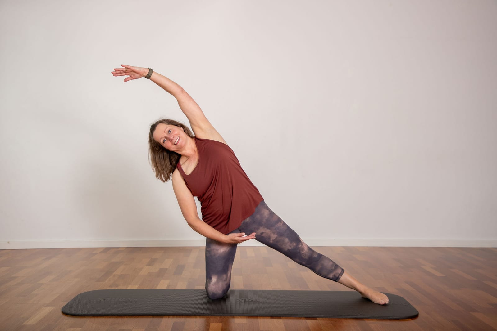 Sabine Löffelmann bei einer seitlichen Pilates-Dehnung auf der Matte im hellen Studio