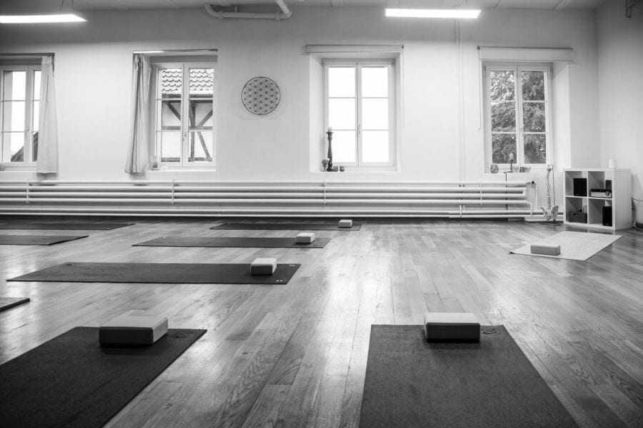 Der helle Kursraum von Bauchzeit mit Yogamatten und einer Blume des Lebens an der Wand