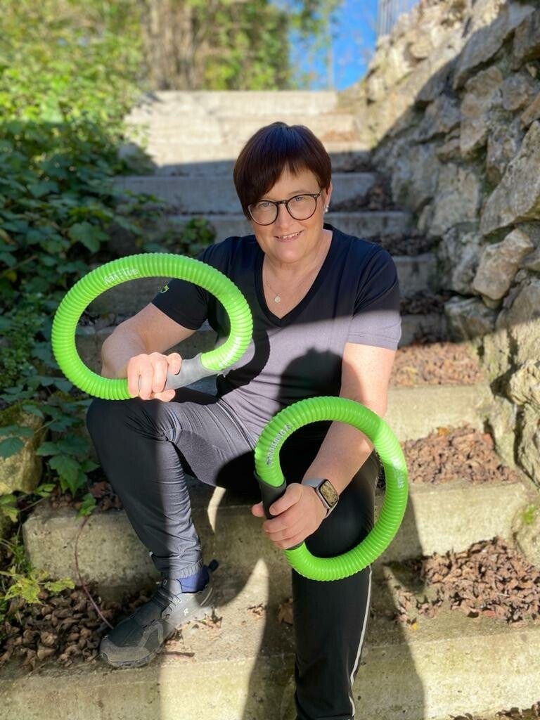 Bettina Hübner sitzt auf einer Steintreppe und hält zwei grüne smovey-Ringe