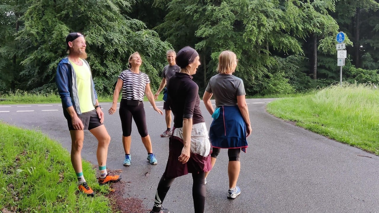 Lachende Gruppe von burpee & run in Laufkleidung auf einem Waldweg bei Bad Waldsee