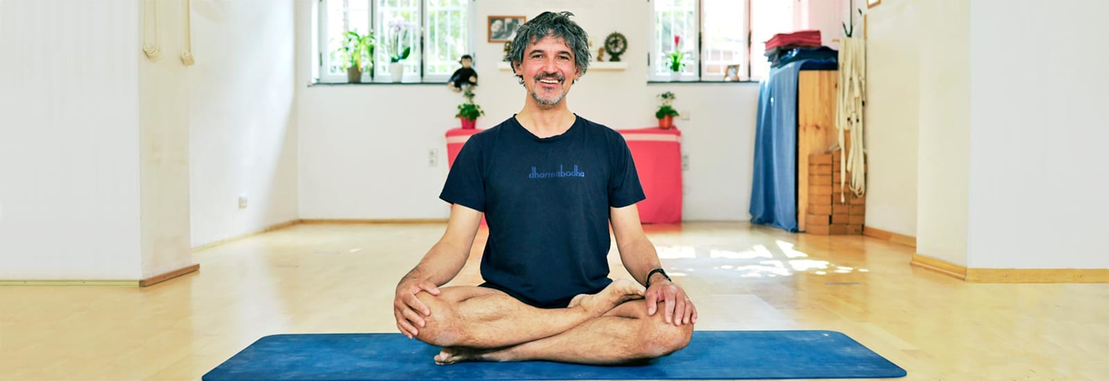 Thorsten Kellermann im Schneidersitz im Yogaraum von dharmabodha in Köln