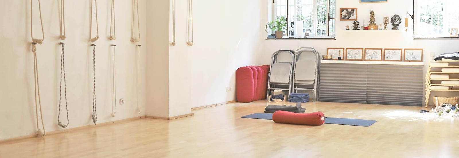 Yogaraum von dharmabodha mit Wandseilen, Bolstern und Iyengar-Zeichnungen
