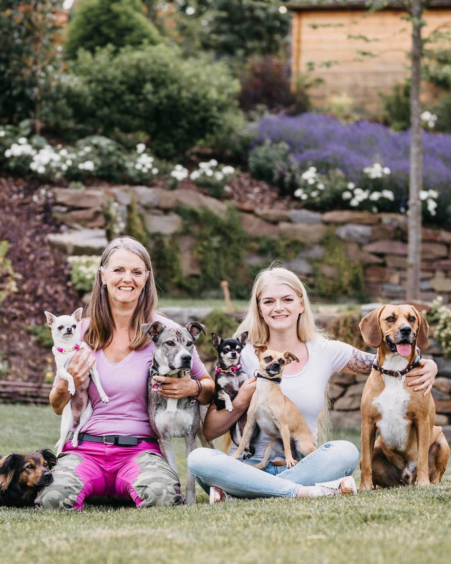 Petra Höfer und ihre Tochter Marleen Schaks sitzen im Garten, ihre sieben Hunde um sie herum