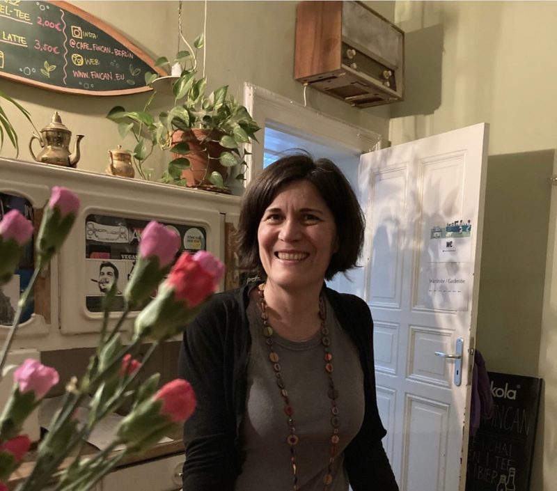 Mensch hinter der Café-Theke im Fincan mit Blumen