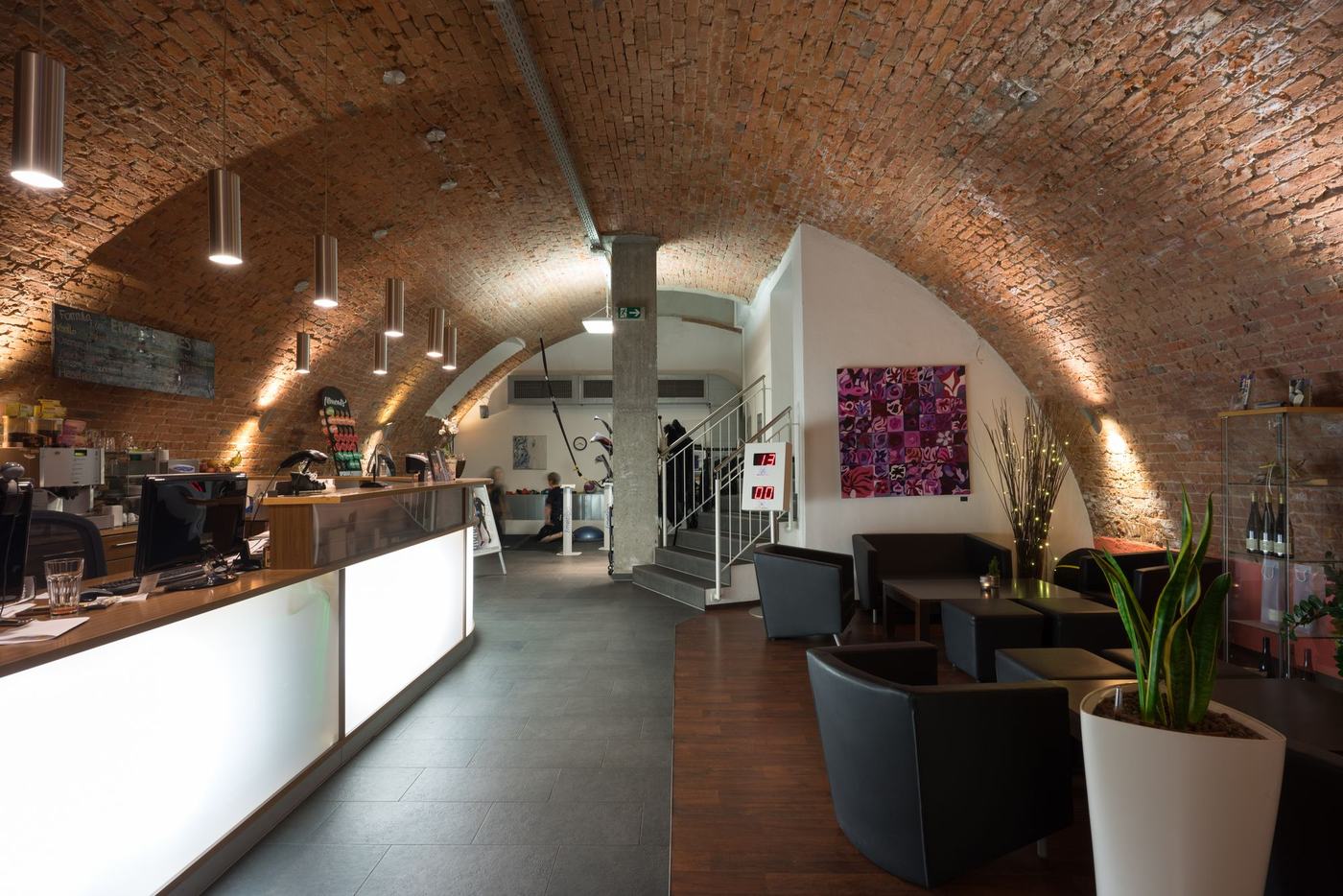Die Lounge der Fitnesslounge Erlangen: beleuchtete Theke und Sessel unter dem historischen Backstein-Gewölbe