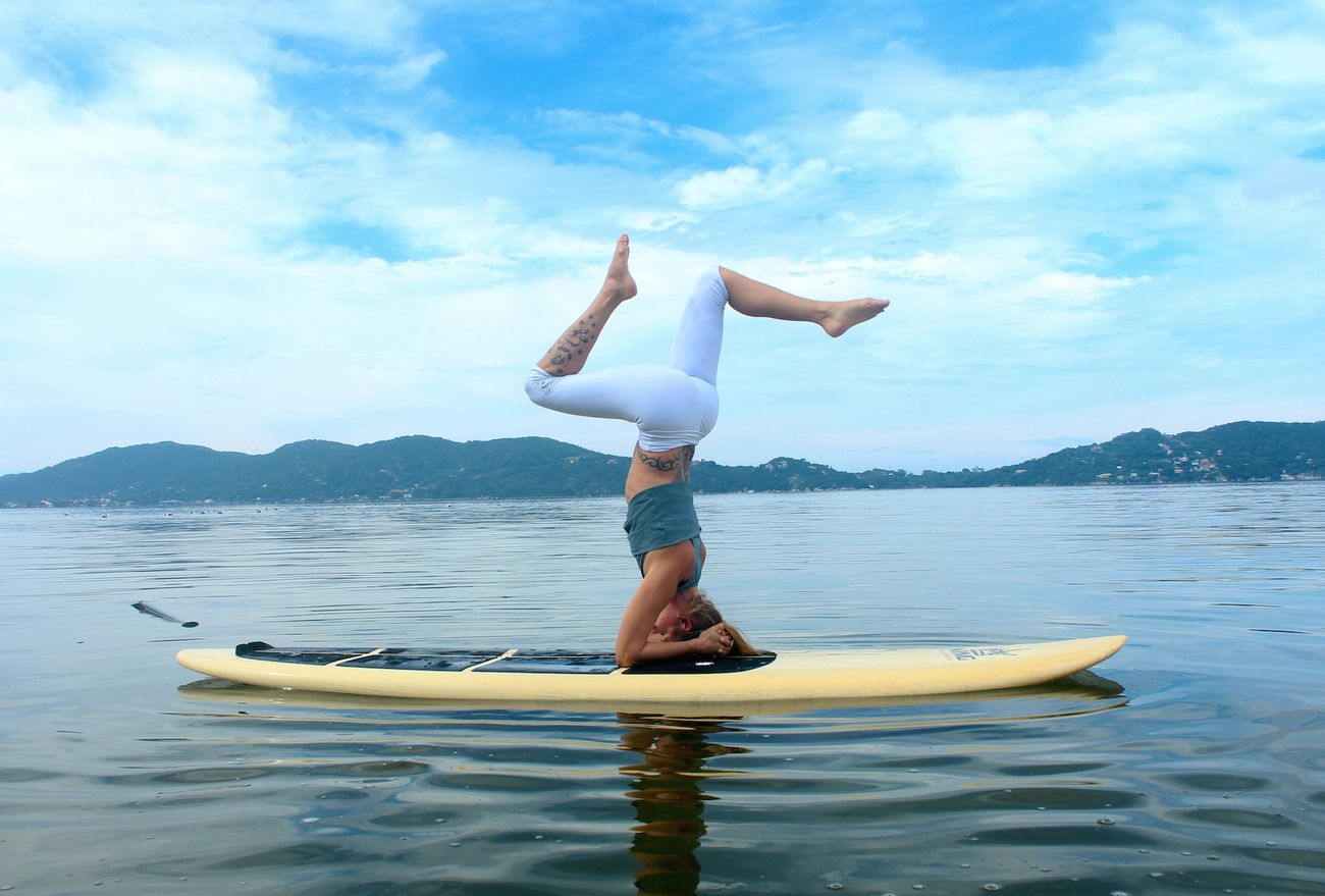 Kopfstand auf dem Stand-Up-Paddle-Board mitten auf dem Wasser, SUP Yoga mit Float & Fly