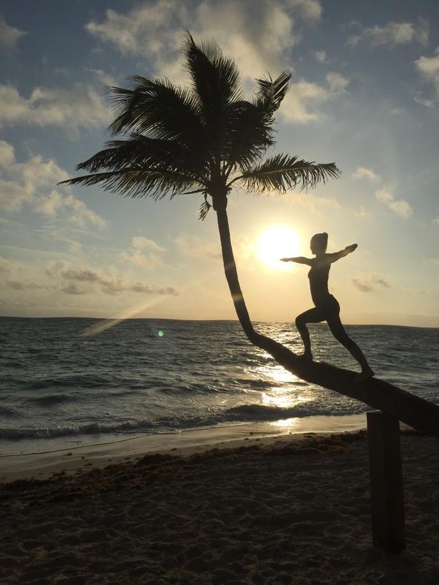 Yoga-Pose auf einer Palme am Strand bei Sonnenaufgang