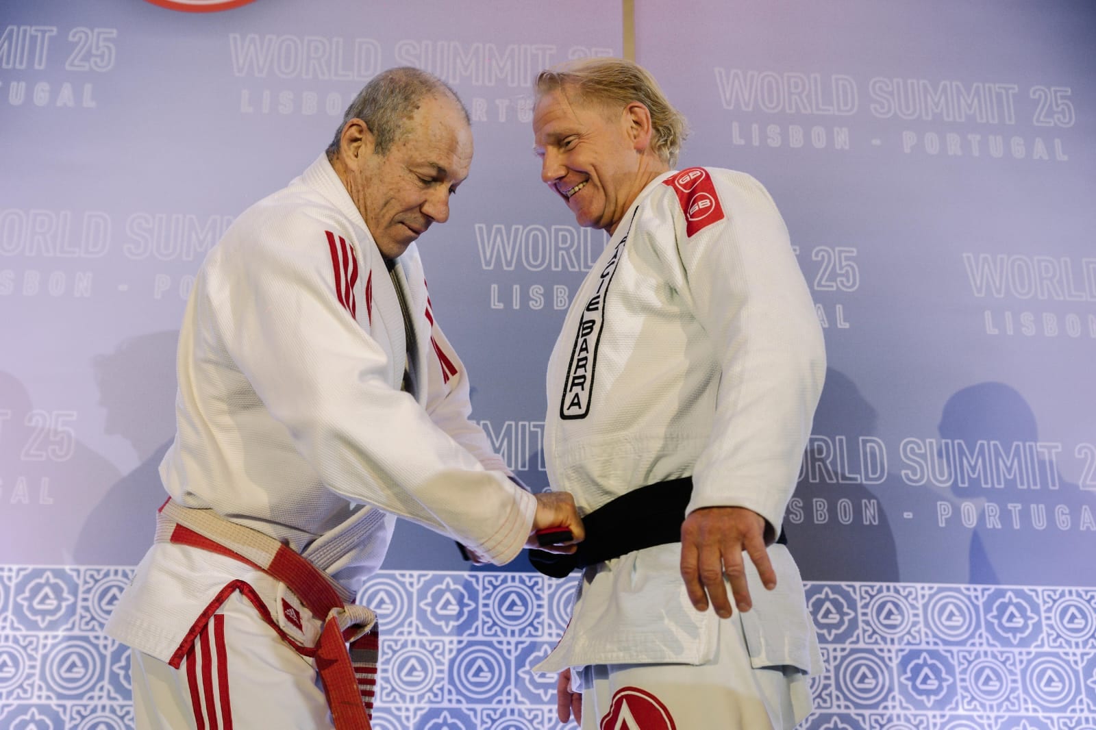 Carlos Gracie Jr. bindet Christian Schön auf dem Gracie Barra World Summit 2025 in Lissabon den schwarzen Gürtel um