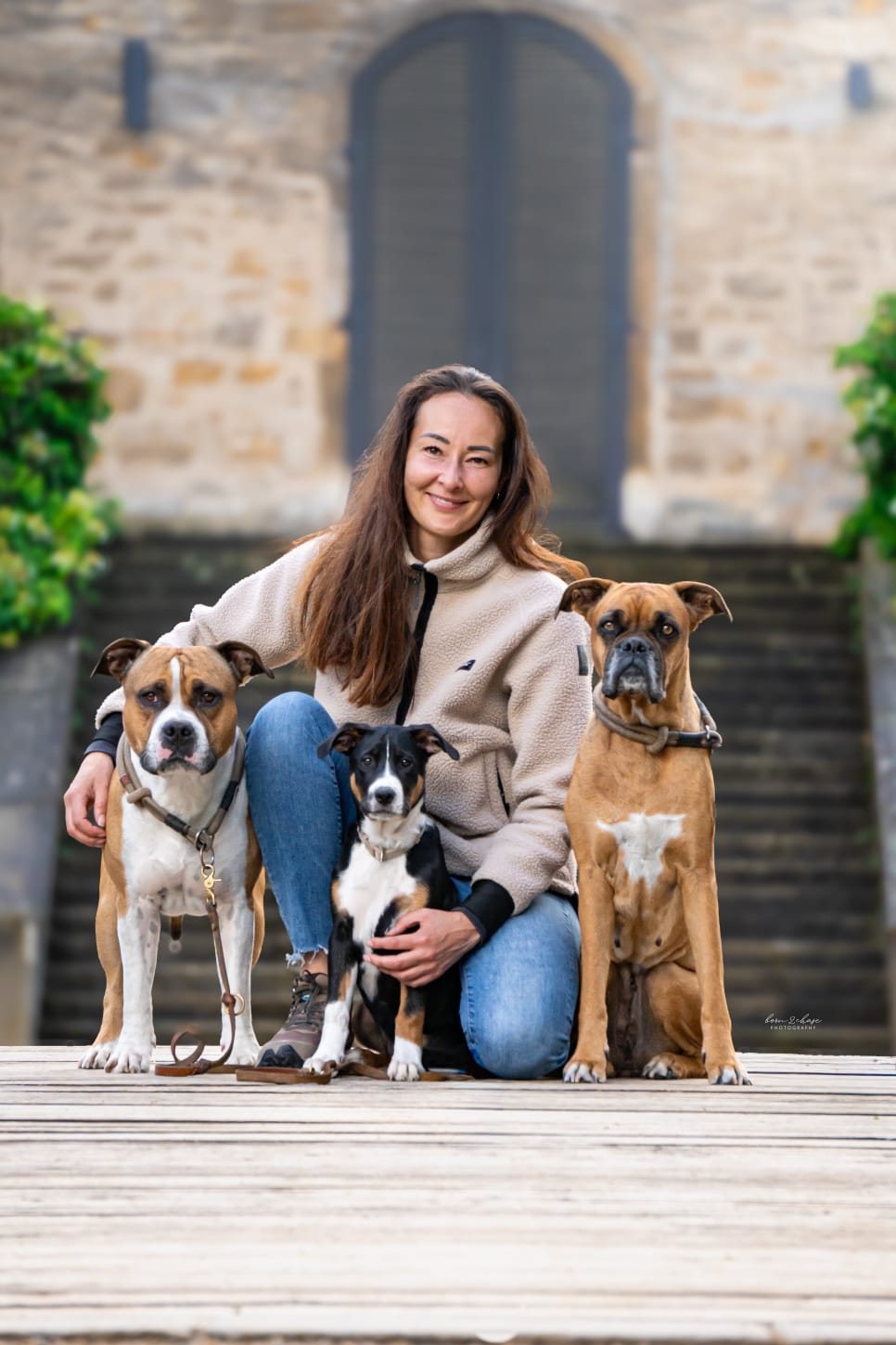 Diana, Hundetrainerin bei HundeGunst, mit ihren drei Hunden auf einem Holzsteg