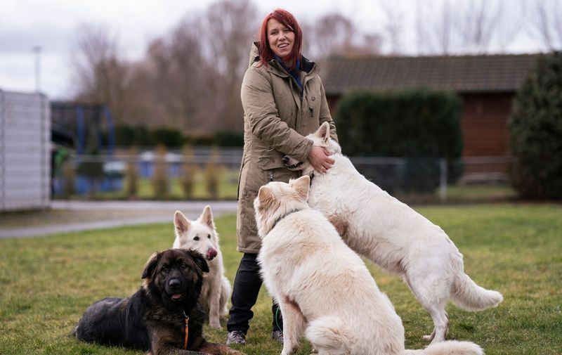Rebecca Voll lacht auf dem Hundeplatz, umgeben von vier Hunden