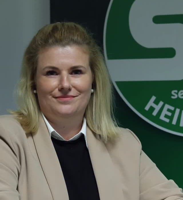 Katrin Zeilberger im hellen Blazer vor dem grünen Vereinslogo des SV Schalding-Heining