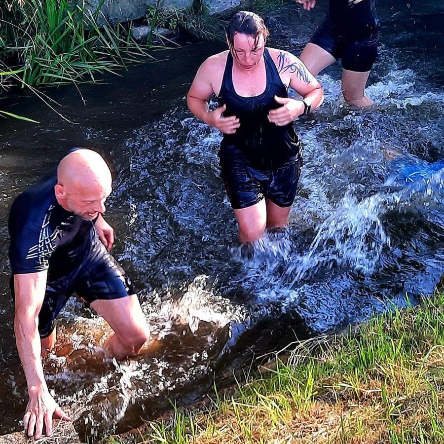 Bootcamp-Teilnehmer waten beim Outdoor-Training durch einen Bach