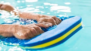 Hände auf einem Schwimmbrett im Wasser