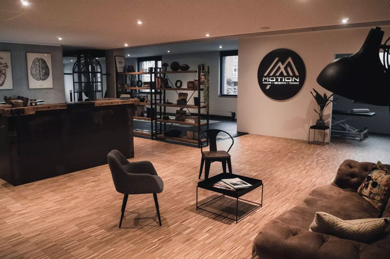 Loft-Empfang von MOTION in Gottmadingen mit rundem Wandlogo, Chesterfield-Sofa und Holzboden