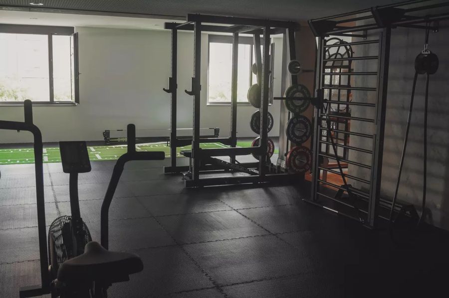 Trainingsfläche von MOTION mit Rack, Hantelscheiben und grüner Kunstrasen-Bahn