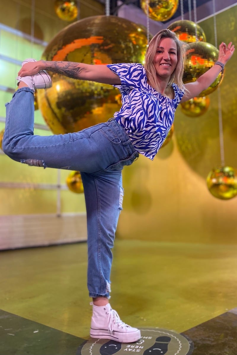 Nicole Prusky in der Tänzer-Haltung vor goldenen Discokugeln