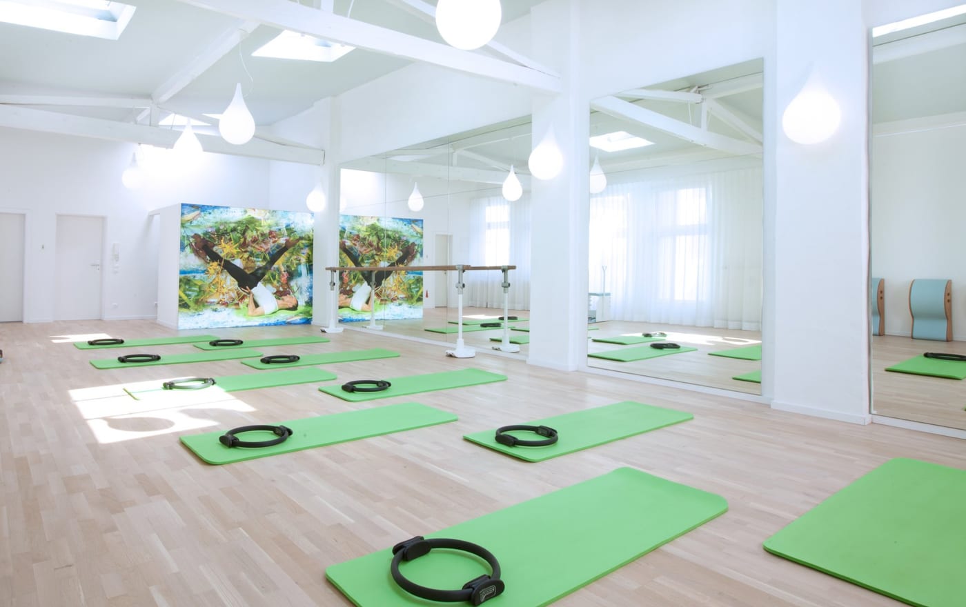 Heller Studioraum von Pilates Essenza mit ausgelegten Pilates-Matten und Spiegelwand