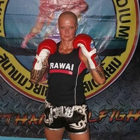 Jule mit roten Boxhandschuhen vor einem Thaiboxen-Banner