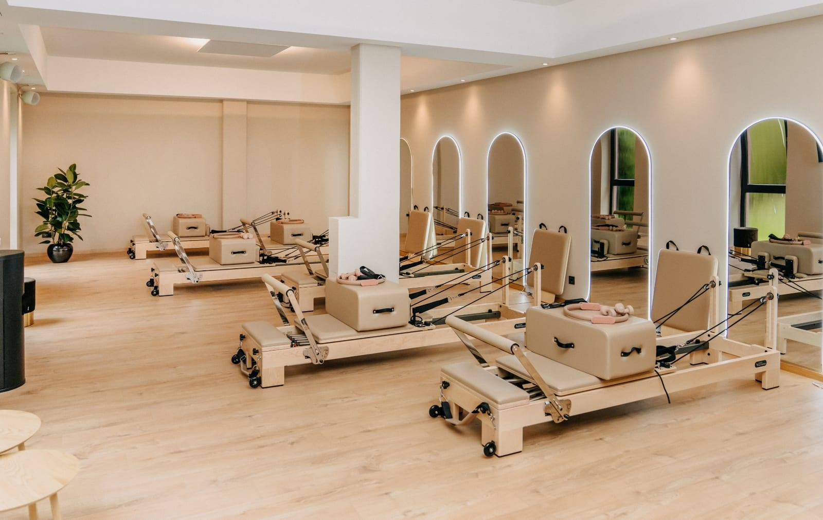 Heller Loft-Raum des Pilates Reformer Loft Attendorn mit sechs Holz-Reformern und beleuchteten Spiegelbögen