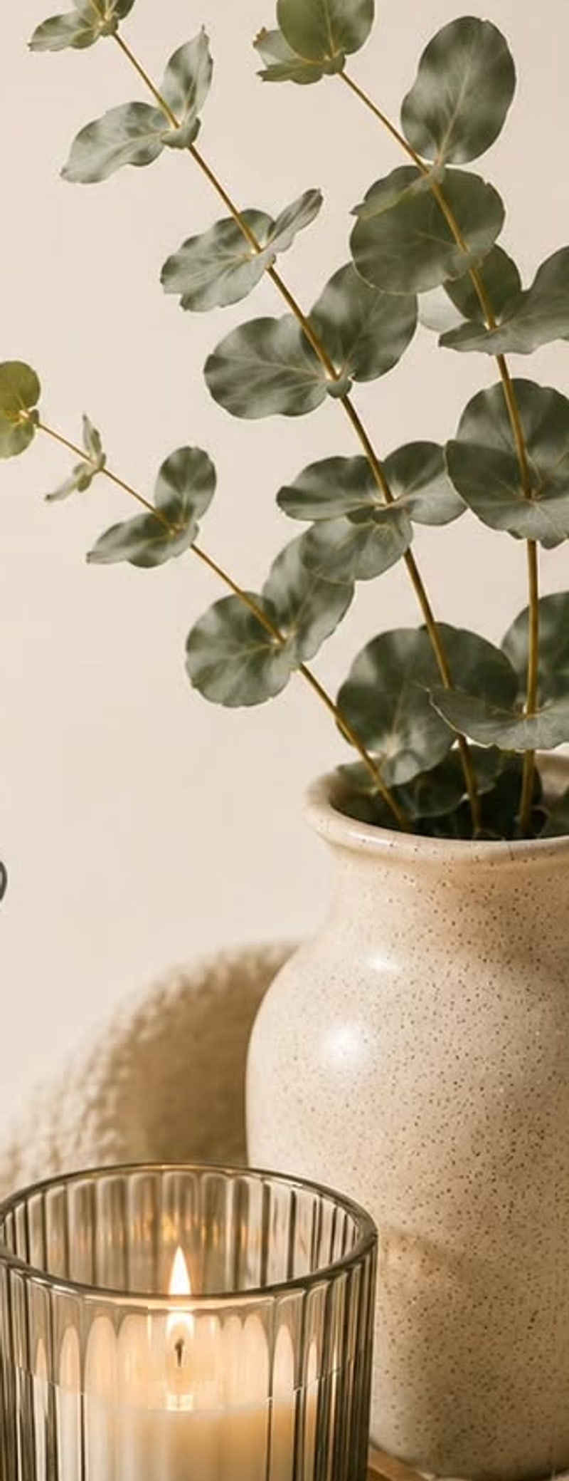 Eukalyptus in einer Steingutvase neben einer brennenden Kerze im RuheRaum