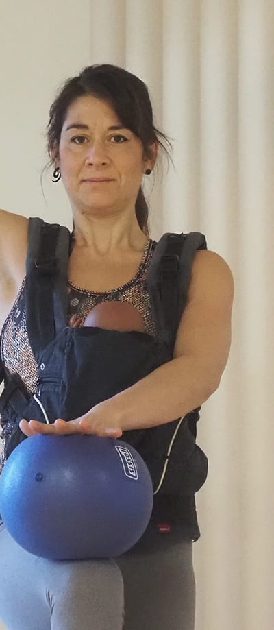 Johanna Roth trainiert mit dem Baby in der Trage und einem Gymnastikball