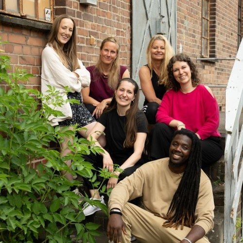 Das internationale Trainerteam von Studio 2 auf einer Backsteintreppe