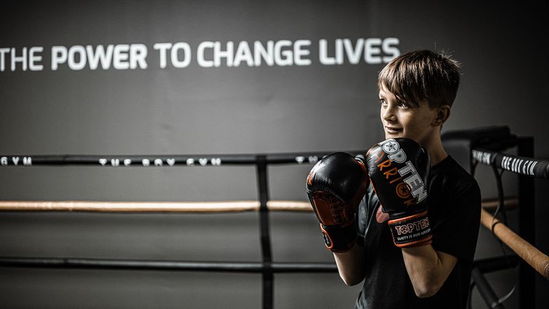 Junger Boxer in Handschuhen vor dem Change-Lives-Schriftzug