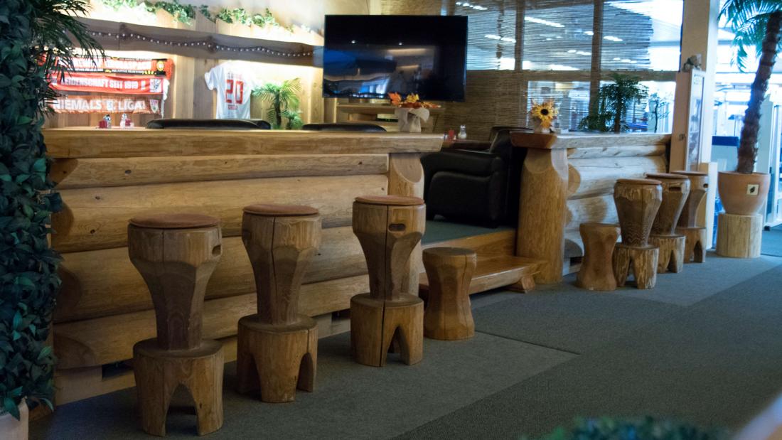 Almhütten-Lounge mit Holzstämmen, Hockern und Shake-Bar