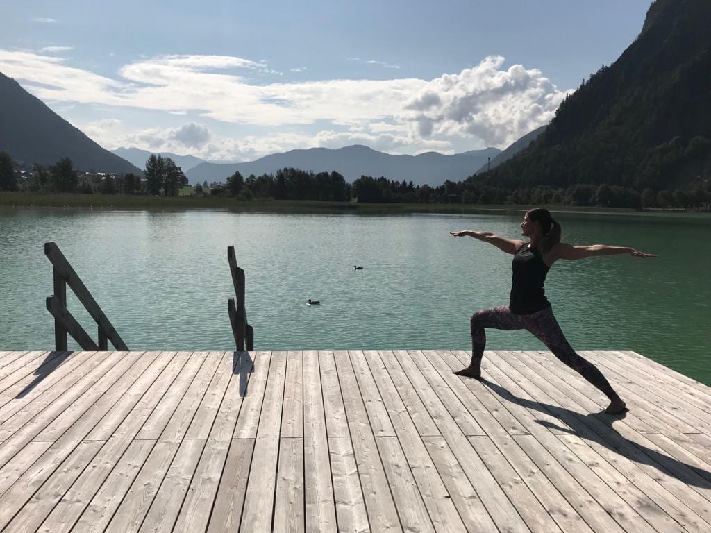 Bianca Gerlach in der Krieger-Haltung auf einem Steg am Bergsee