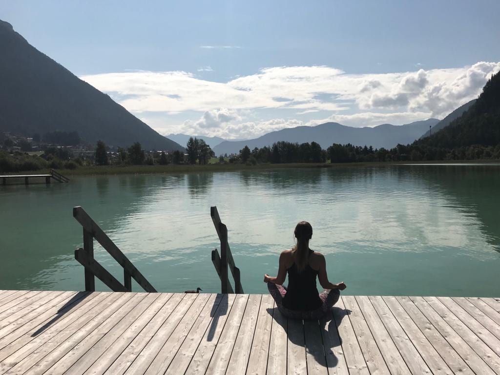 Bianca Gerlach in Meditation auf einem Steg am See
