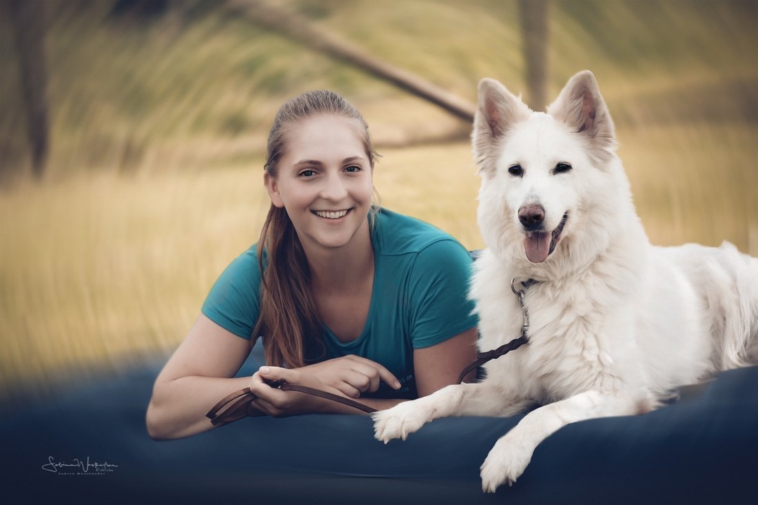 Trainerin mit einem Weißen Schäferhund auf der Wiese bei Zusammenspiel MenschHund
